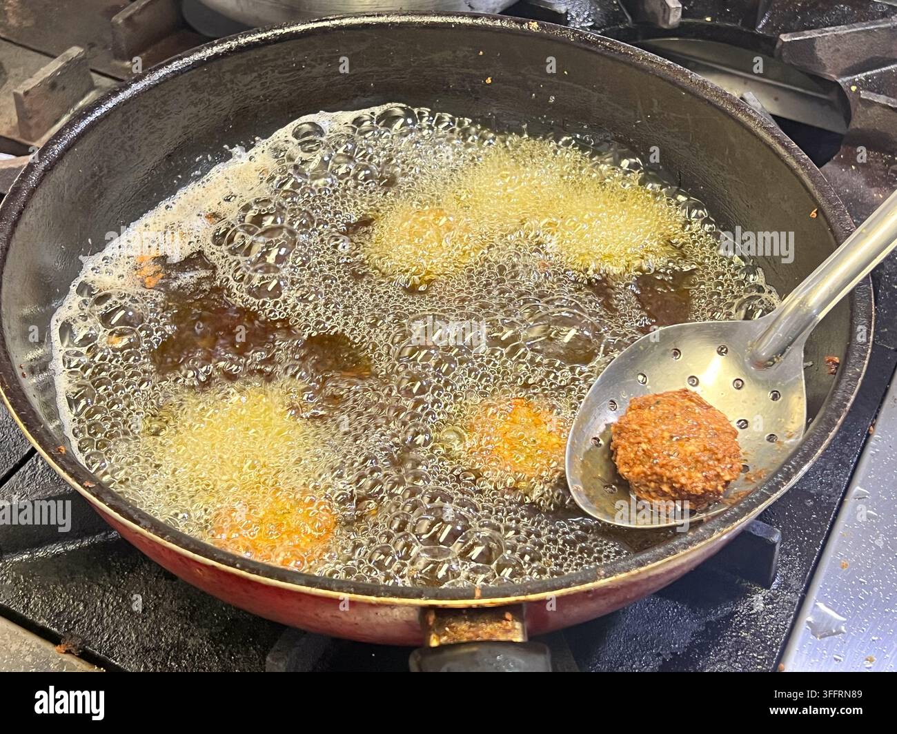 Boulettes de falafel frites dans une poêle à frire. Le falafel est une boule ou une galette frite d'origine égyptienne, dans une cuisine. Banque D'Images