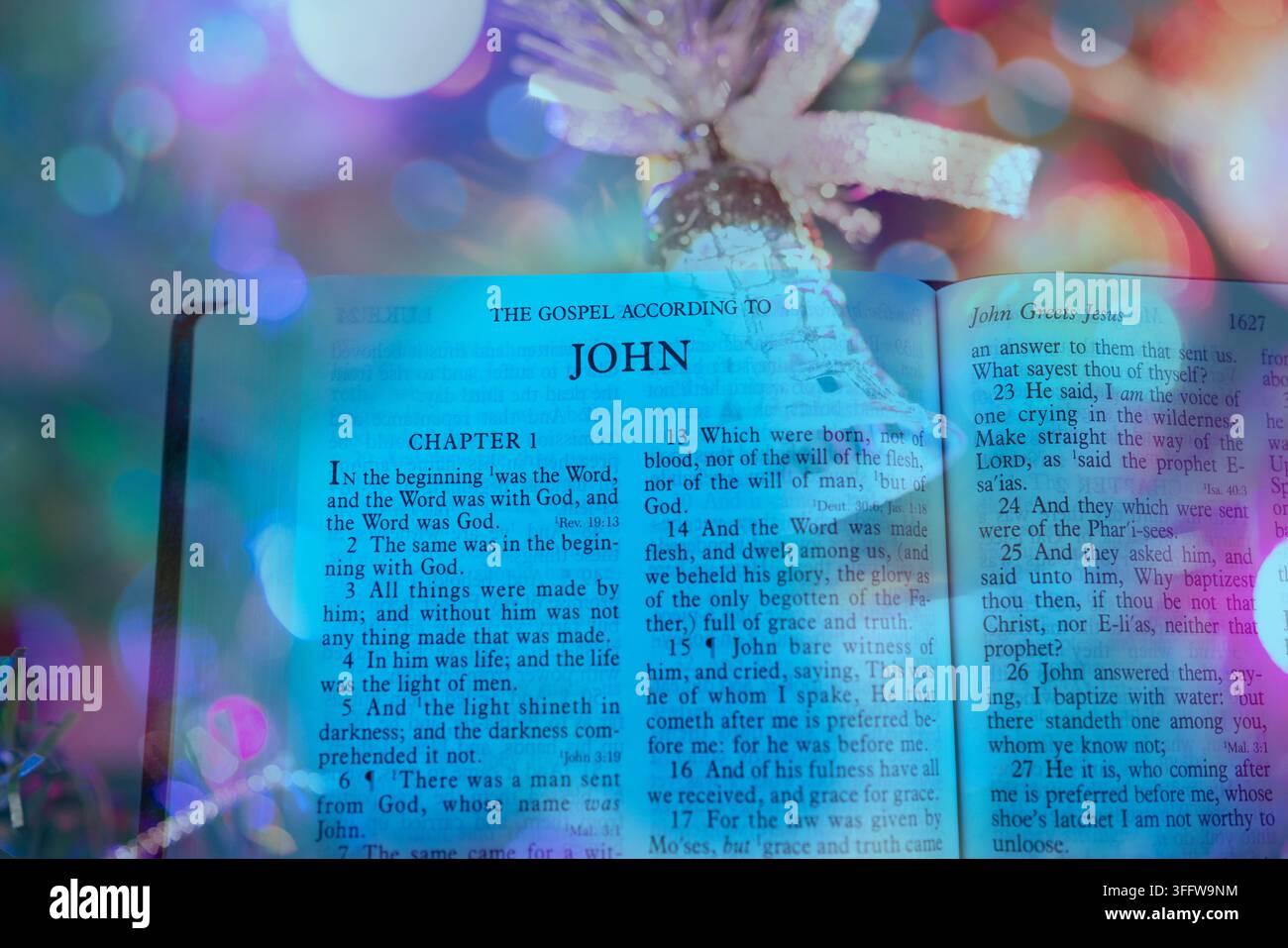 Un livre de la Sainte Bible ouvert montrant le sujet de l'Évangile de Jean, illuminé par des lumières festives douces, un rappel que la Parole apporte la vie, la lumière et la grâce Banque D'Images