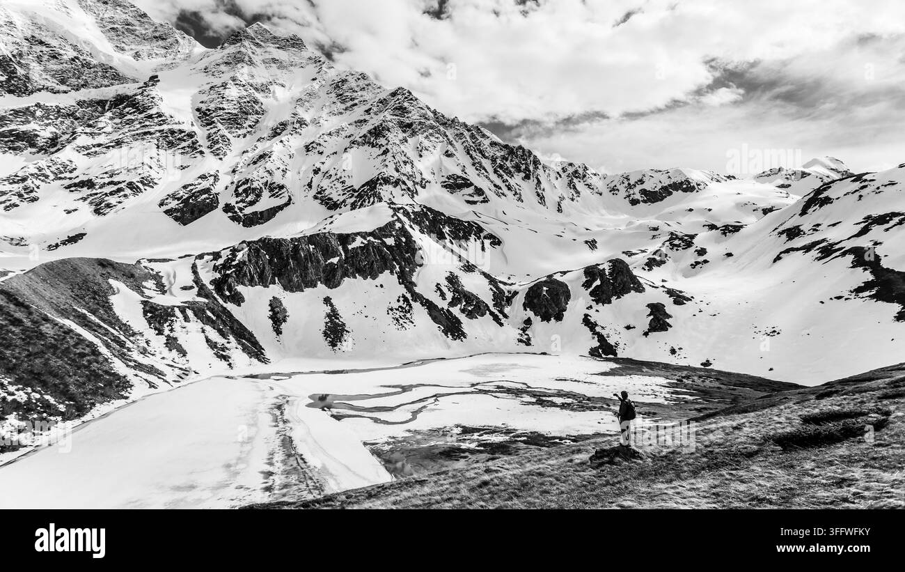 Touriste filmant le lac de haute montagne gelé Donguz-Orun Kol avec une caméra vidéo, région d'Elbrouss. Banque D'Images