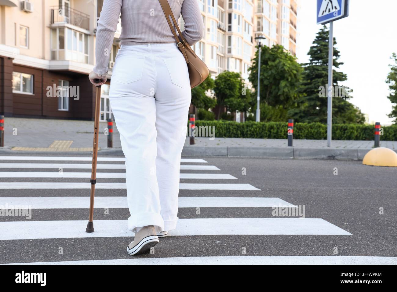 Soutien à l'accessibilité et à la mobilité, femme marchant sur un passage piéton avec une canne pour la rééducation physique et une vie indépendante en milieu urbain Banque D'Images