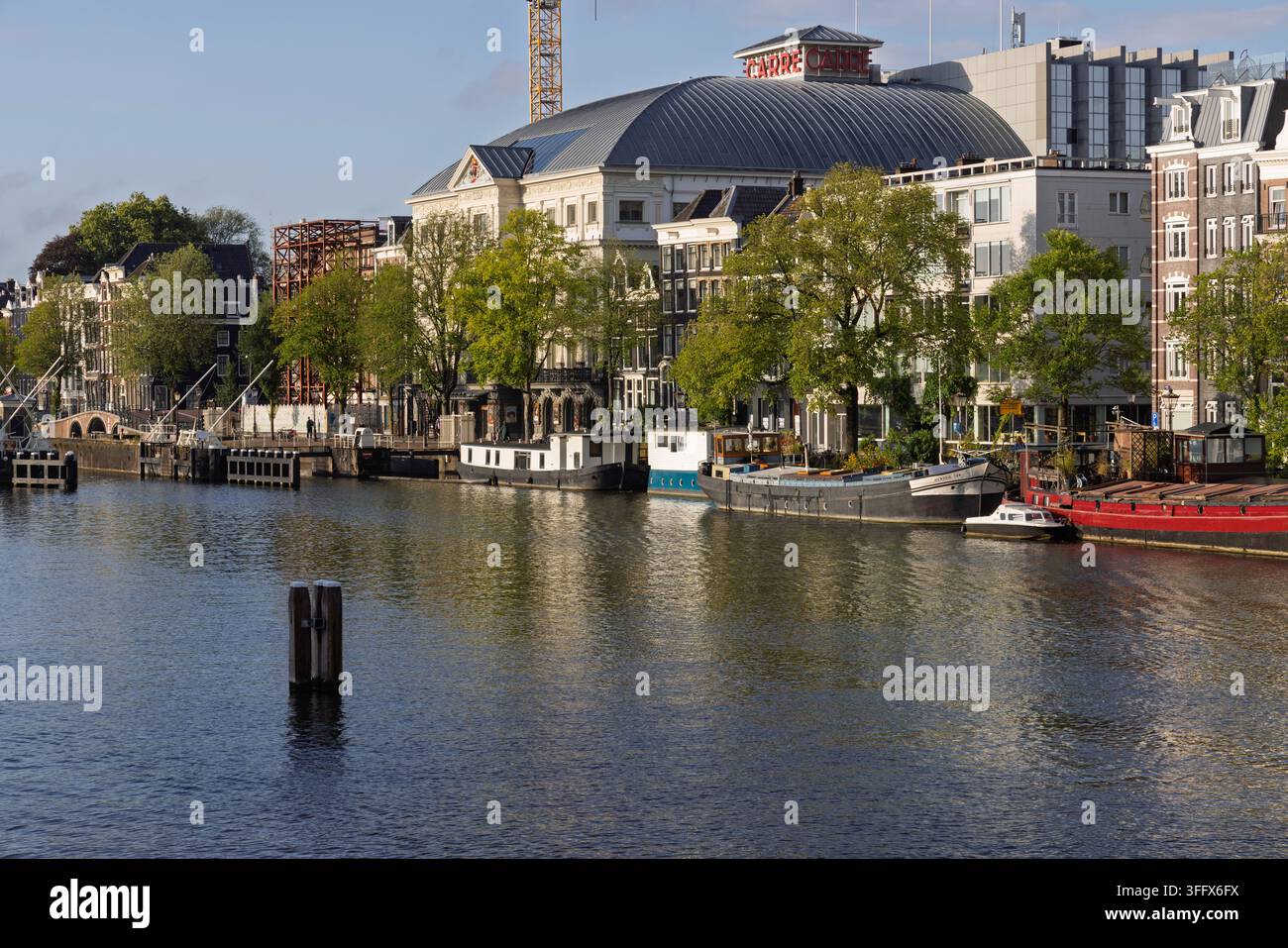 Amsterdam, Pays-Bas – 28 août 2026 : Façade historique du Royal Theatre Carre vue depuis l’eau avec des maisons bateaux traditionnelles amarrées sur le Banque D'Images