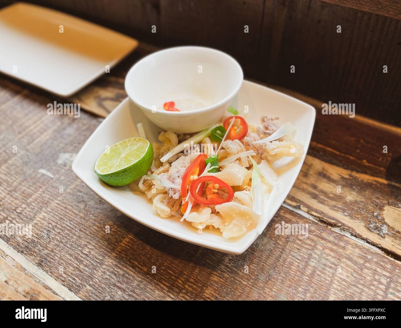 Calmars croustillants au sel et au poivre garnis de piment rouge frais, d'oignon de printemps et d'une tranche de lime, dans un restaurant vietnamien, Angleterre, Royaume-Uni Banque D'Images