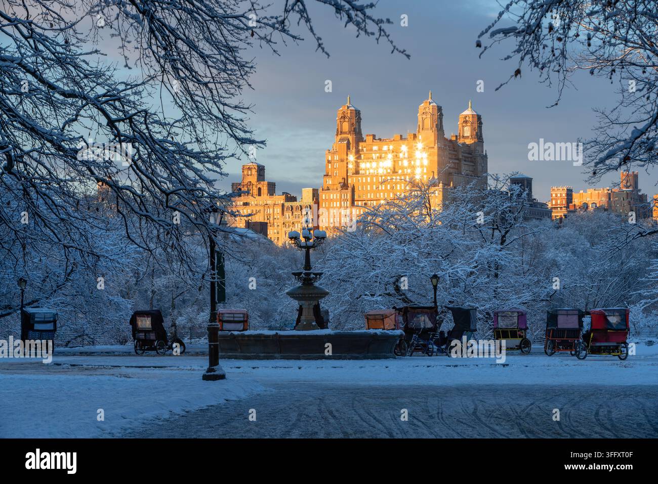 Scène d'hiver dans Central Park après une tempête de neige, avec des arbres enneigés et un bâtiment illuminé par le coucher de soleil dans l'Upper West Side, Manhattan, New York City Banque D'Images