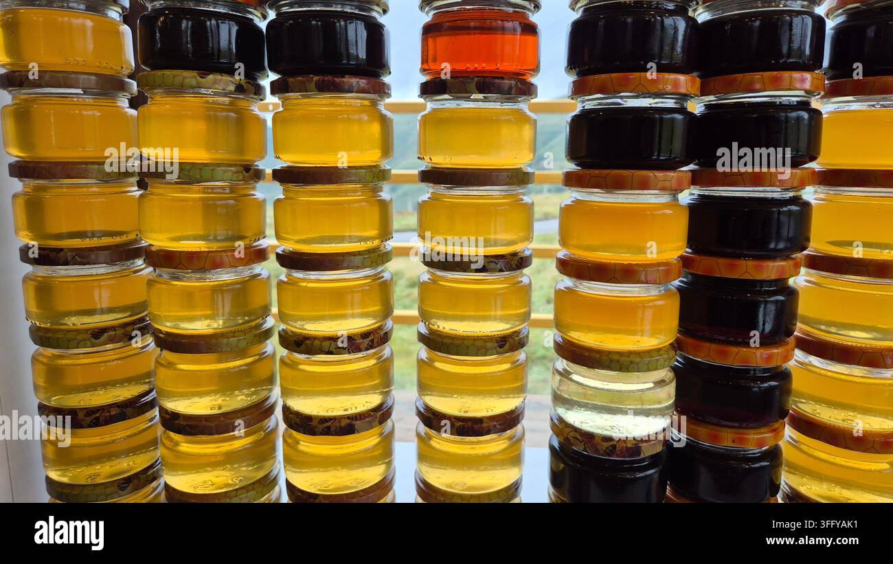 Bocaux de miel naturel bio pur dans diverses teintes ambrées dorées exposés sur un marché d'un village géorgien - Image de stock capturée avec un smartphone