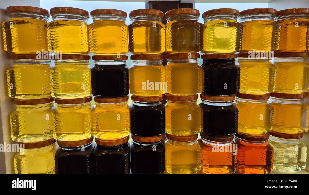 Bocaux de miel naturel bio pur dans diverses teintes ambrées dorées exposés sur un marché d'un village géorgien - Image de stock capturée avec un smartphone