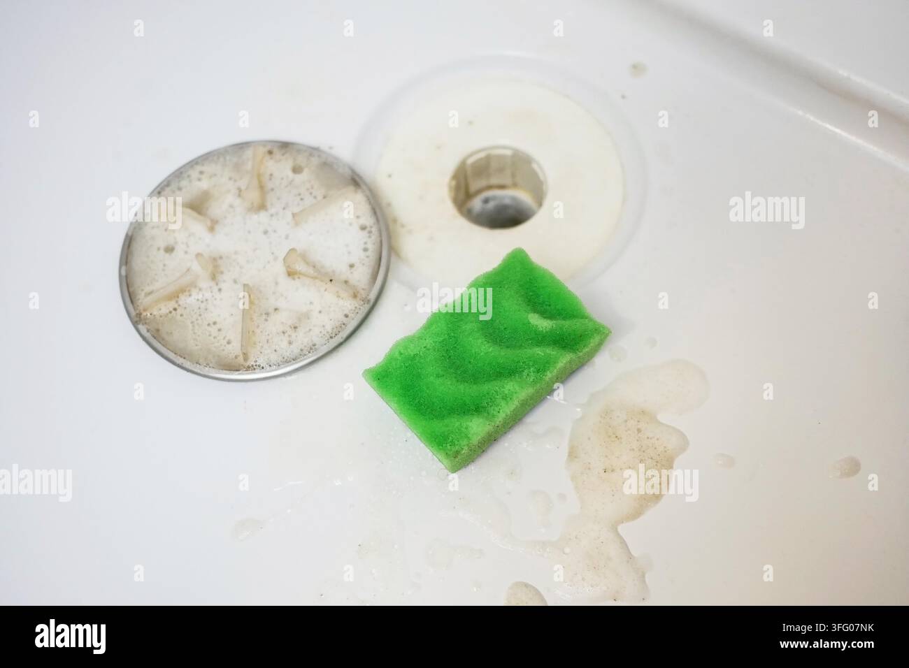 Close-up d'un drain de douche recouvert de mousse de savon douce et d'une éponge - une image simple de propreté, de soins quotidiens et de routine de salle de bain bien rangée. Banque D'Images