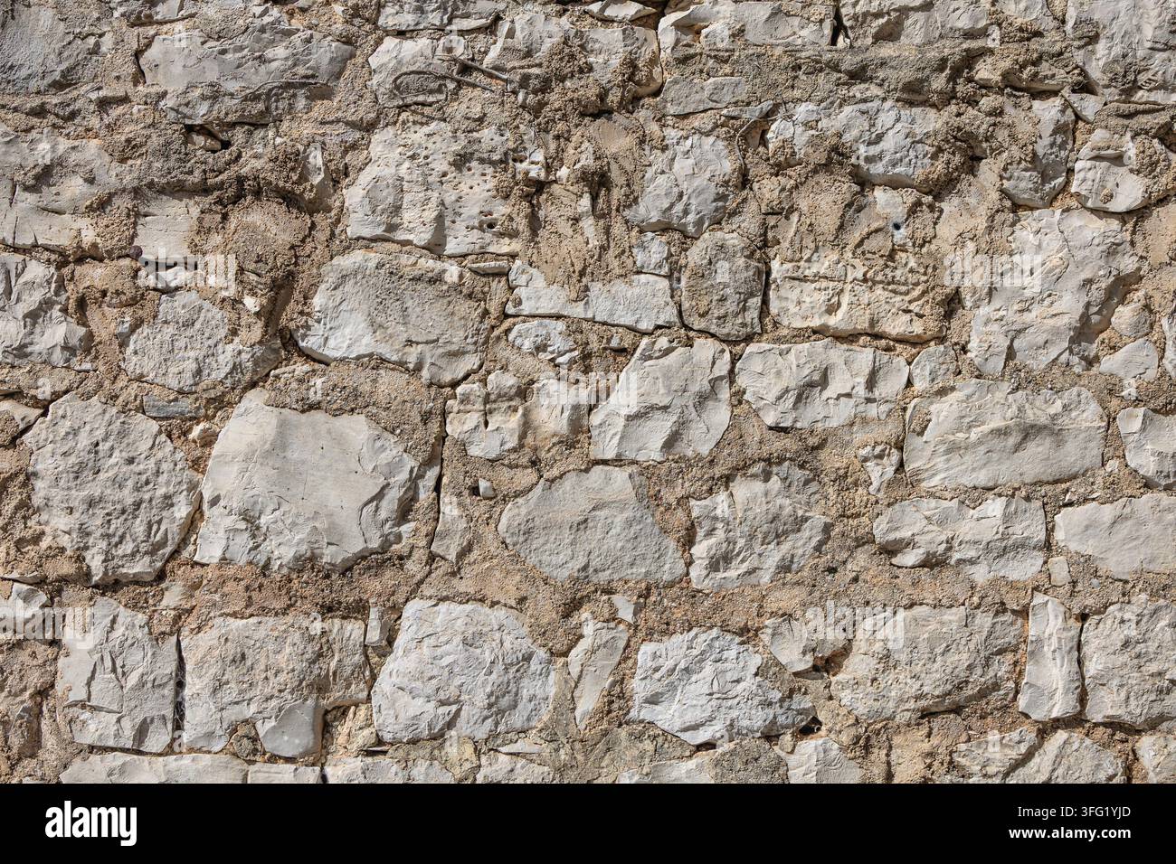 Mur de calcaire rugueux composé de blocs irréguliers et de mortier sablonneux, mettant en valeur une texture érodée et un caractère rustique. Idéal pour un arrière-plan architectural Banque D'Images