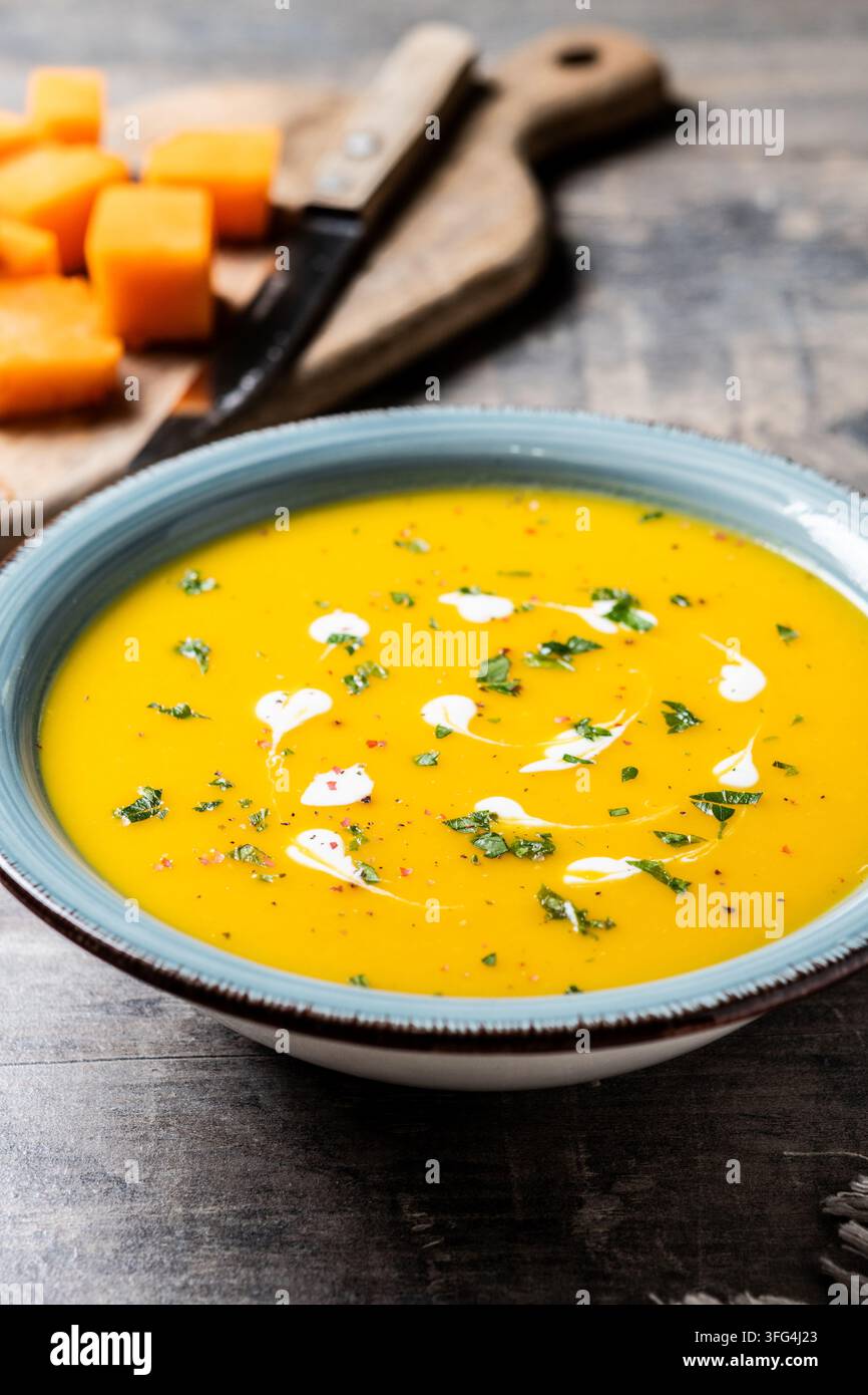 Soupe crémeuse de citrouille aux herbes et à la crème sur une table en bois Banque D'Images