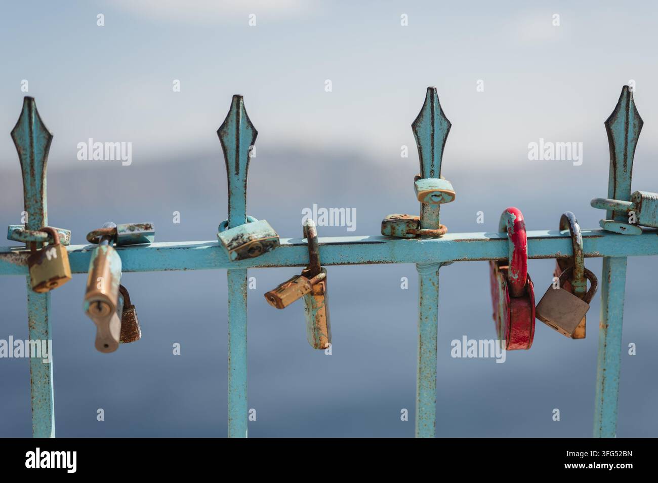 Serrures d'amour rouillées accrochées à une clôture bleue patinée à Santorini Banque D'Images