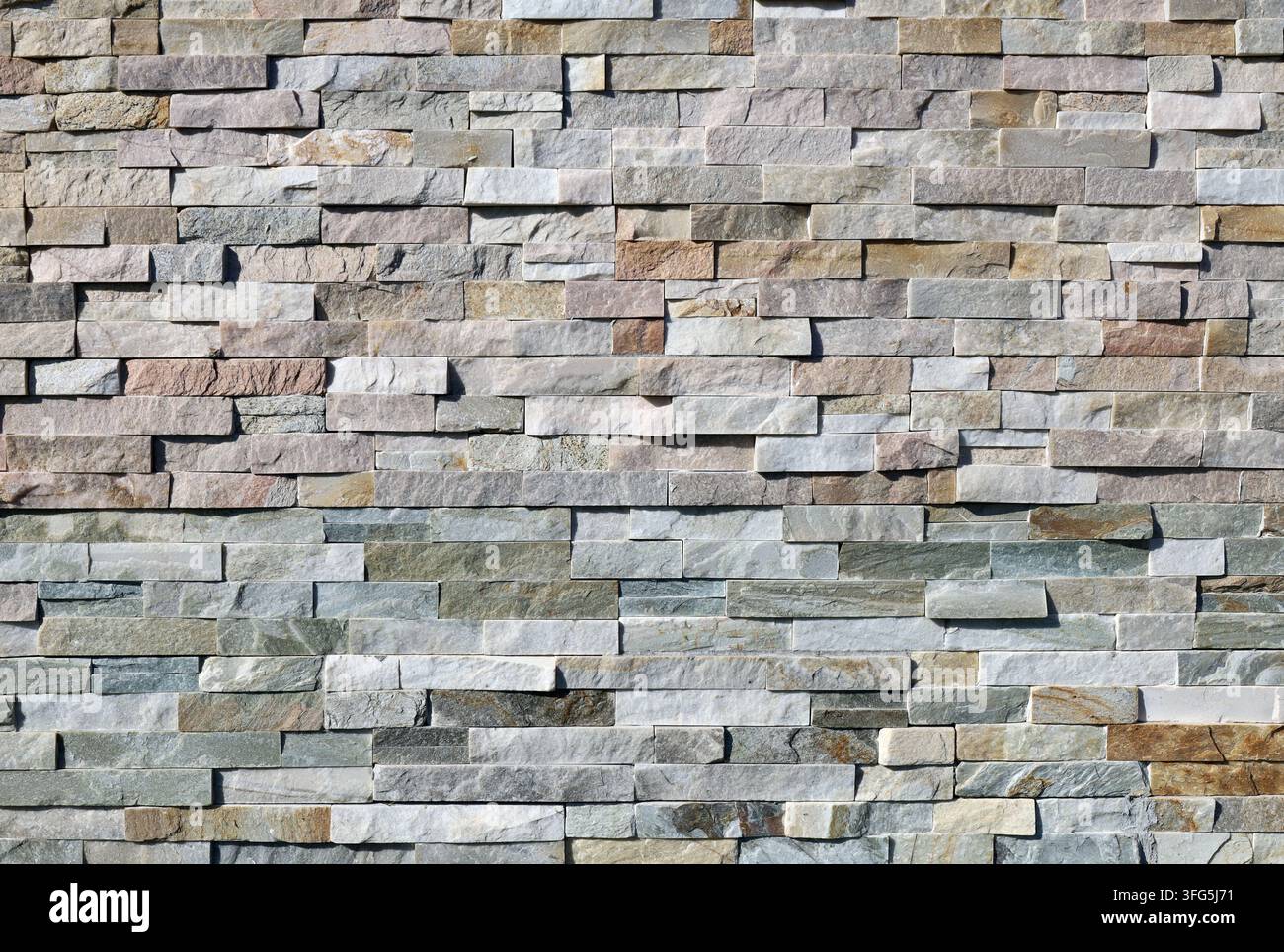 Revêtement mural en bandes de quartzite multicolore et d'ardoise. Cadre complet, fond et texture. Banque D'Images