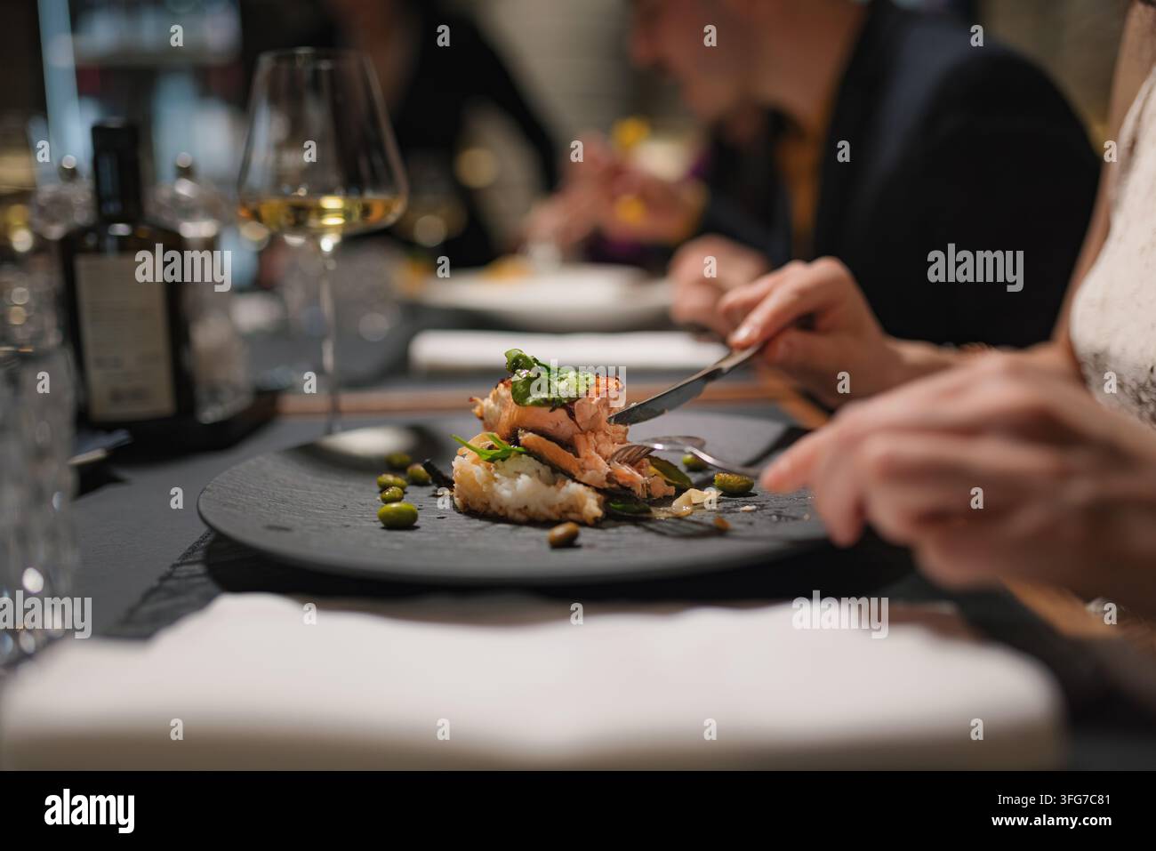 Groupe d'amis dînant ensemble dans un restaurant haut de gamme, profitant de leur repas et de leurs boissons. Banque D'Images