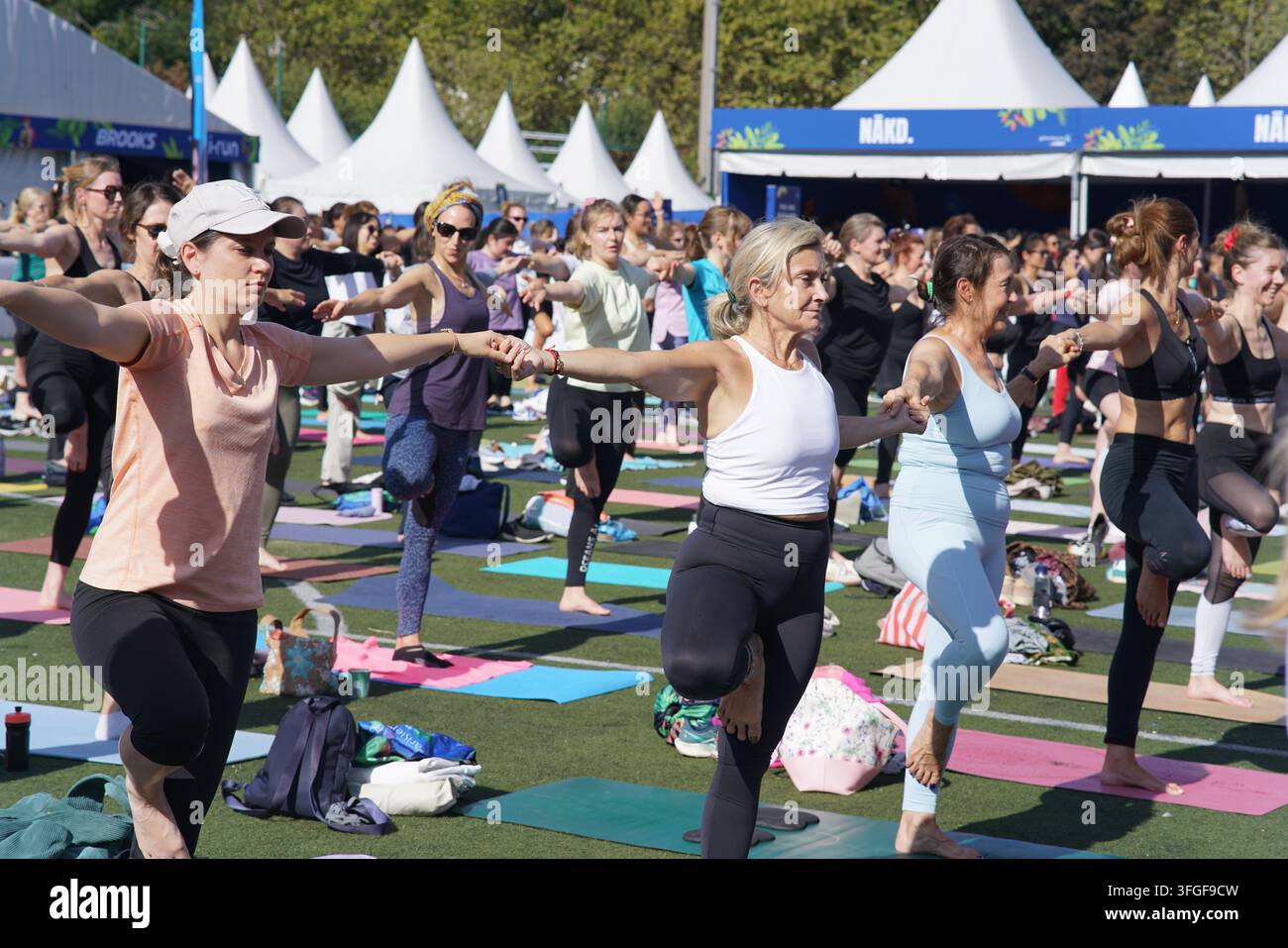 Grand groupe de femmes participant à une séance d'échauffement de yoga avant l'événement de course féminine La Parisienne sur un terrain extérieur à Paris, France. Banque D'Images
