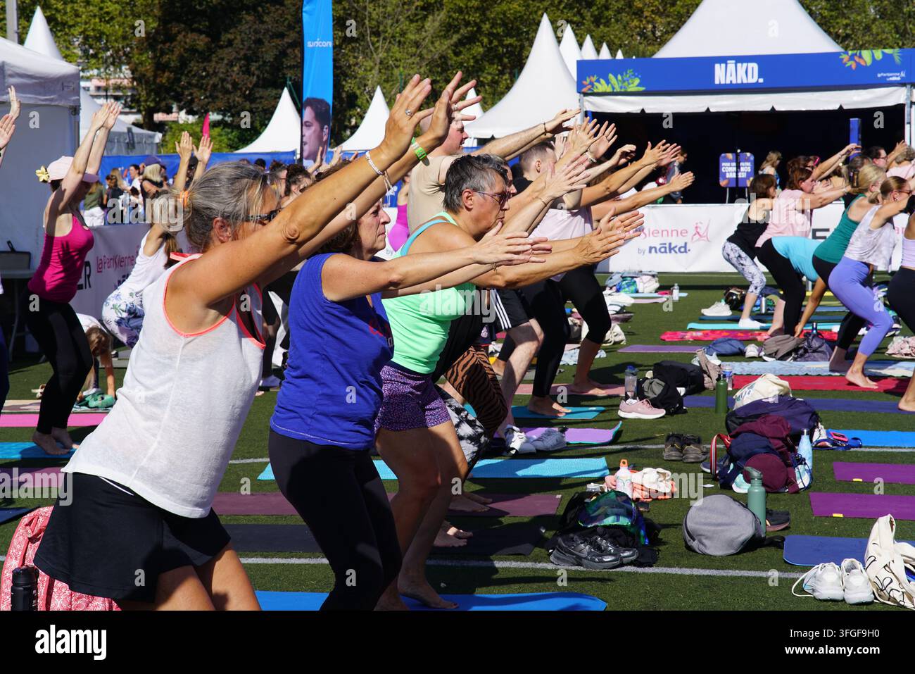 Grand groupe de femmes participant à une séance d'échauffement de yoga avant l'événement de course féminine La Parisienne sur un terrain extérieur à Paris, France. Banque D'Images