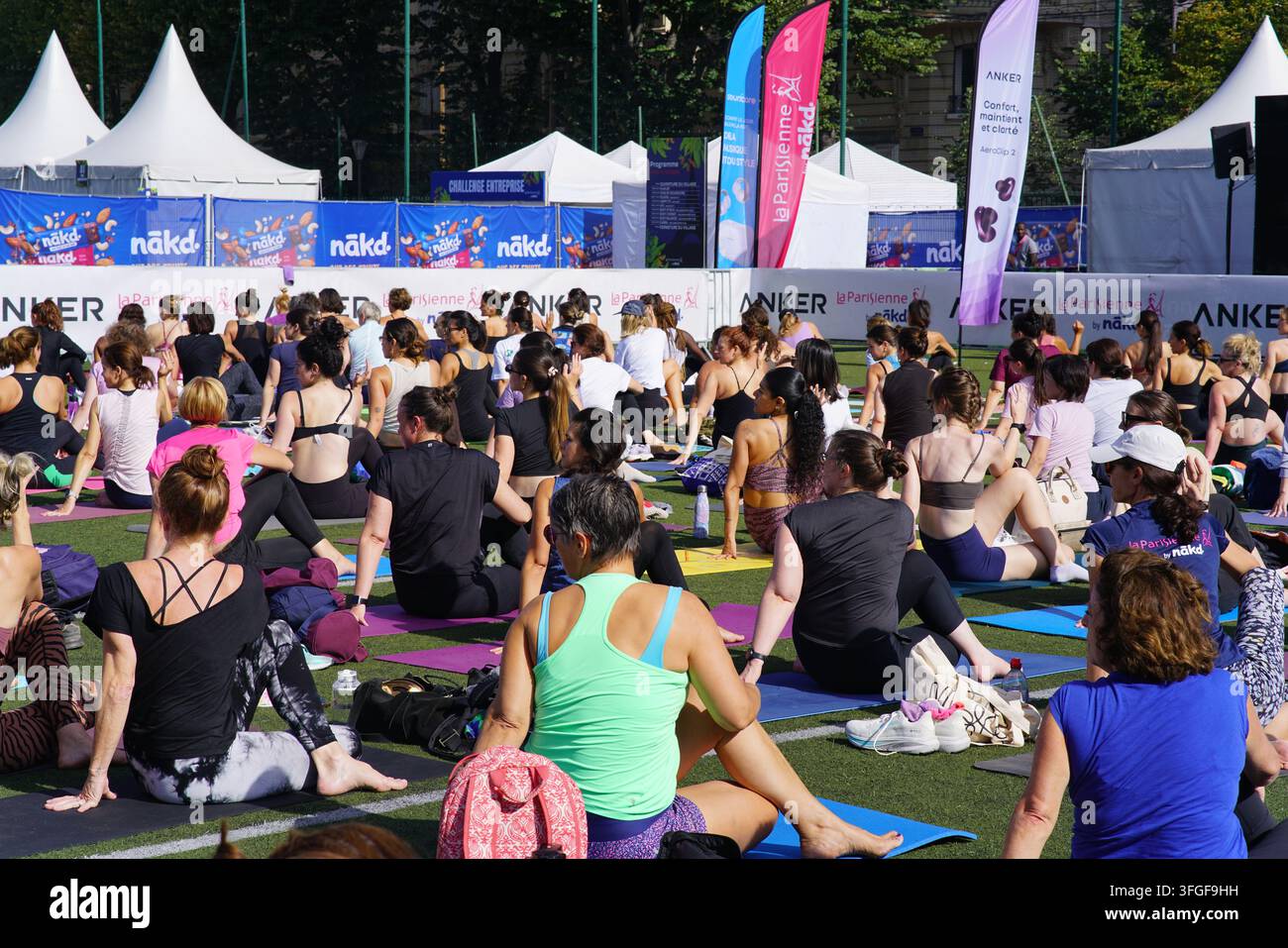 Grand groupe de femmes participant à une séance d'échauffement de yoga avant l'événement de course féminine La Parisienne sur un terrain extérieur à Paris, France. Banque D'Images