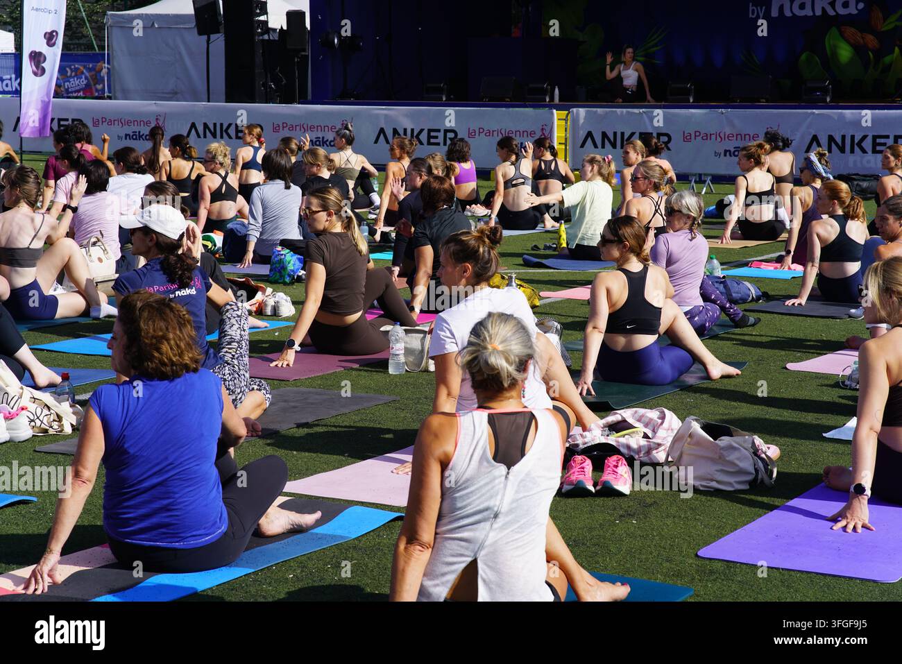Grand groupe de femmes participant à une séance d'échauffement de yoga avant l'événement de course féminine La Parisienne sur un terrain extérieur à Paris, France. Banque D'Images