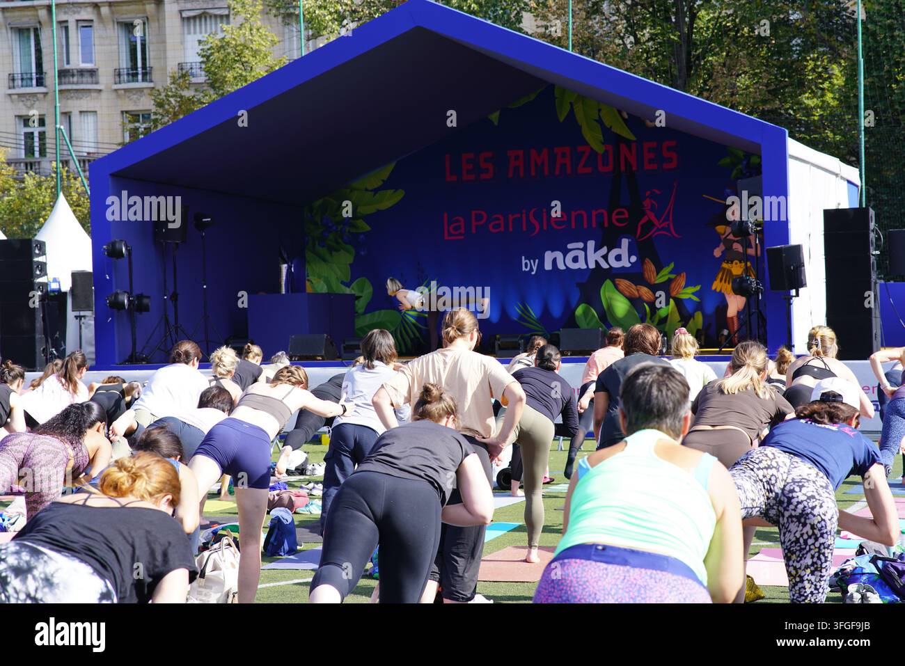 Grand groupe de femmes participant à une séance d'échauffement de yoga avant l'événement de course féminine La Parisienne sur un terrain extérieur à Paris, France. Banque D'Images