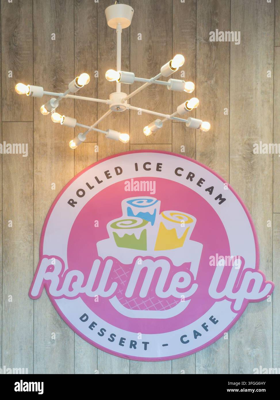 Intérieur d'un café à glace moderne mettant en vedette un box jaune vif et une enseigne murale élégante pour la glace roulée 'Roll Me Up'. La décoration combine Rus - Image de stock capturée avec un smartphone