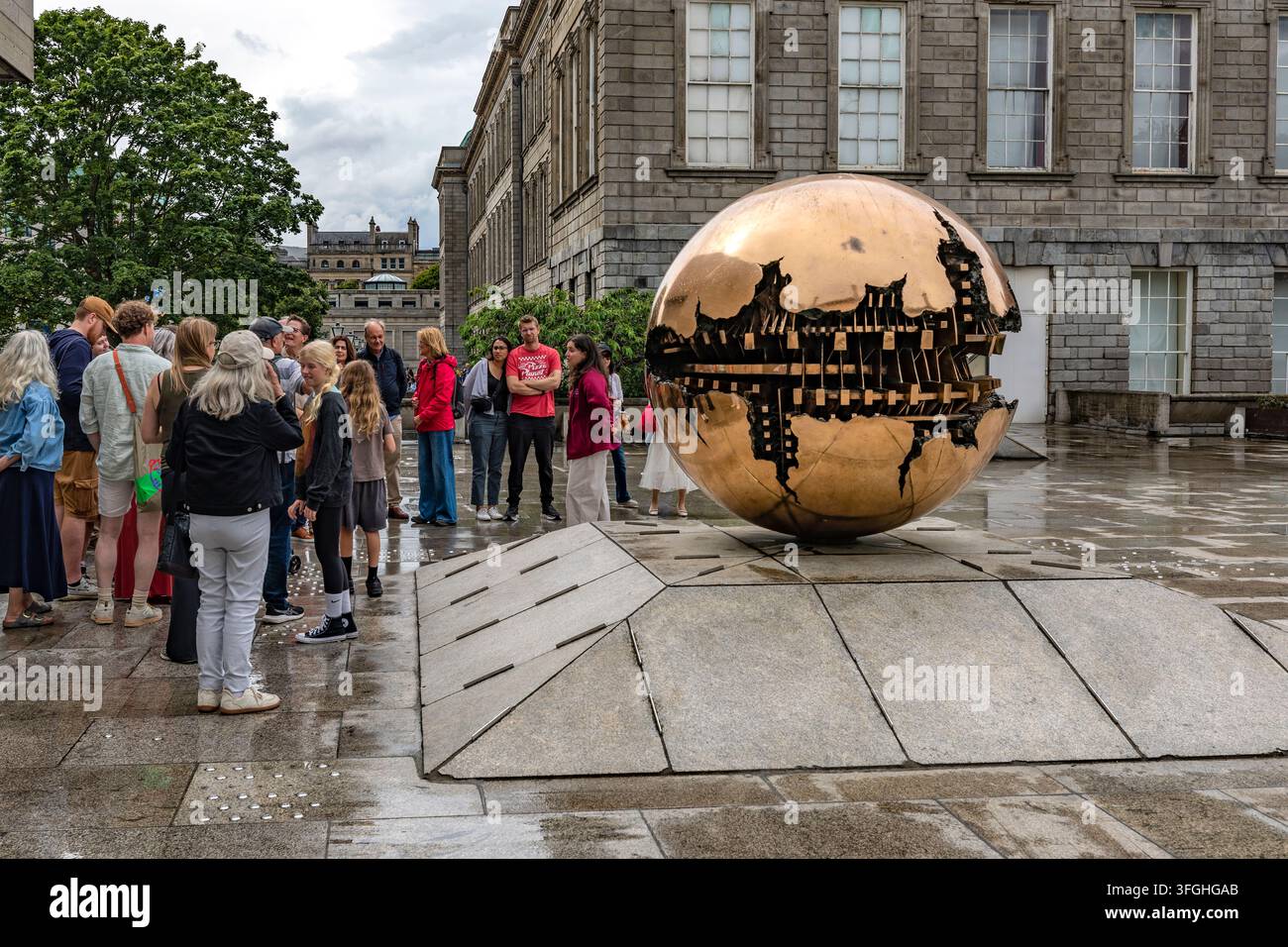 Les visiteurs se rassemblent autour de Sfera con Sfera, une sculpture globe en bronze d'Arnaldo Pomodoro, à l'extérieur de la bibliothèque Berkeley du Trinity College à Dublin, Irlande Banque D'Images