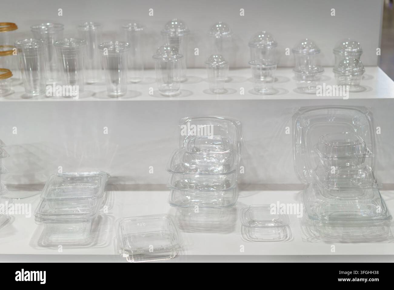 Une étagère d'exposition montrant une assortiment de contenants d'emballage alimentaire en plastique transparent vides, y compris des gobelets avec des couvercles en dôme et diverses boîtes pour la restauration. Banque D'Images