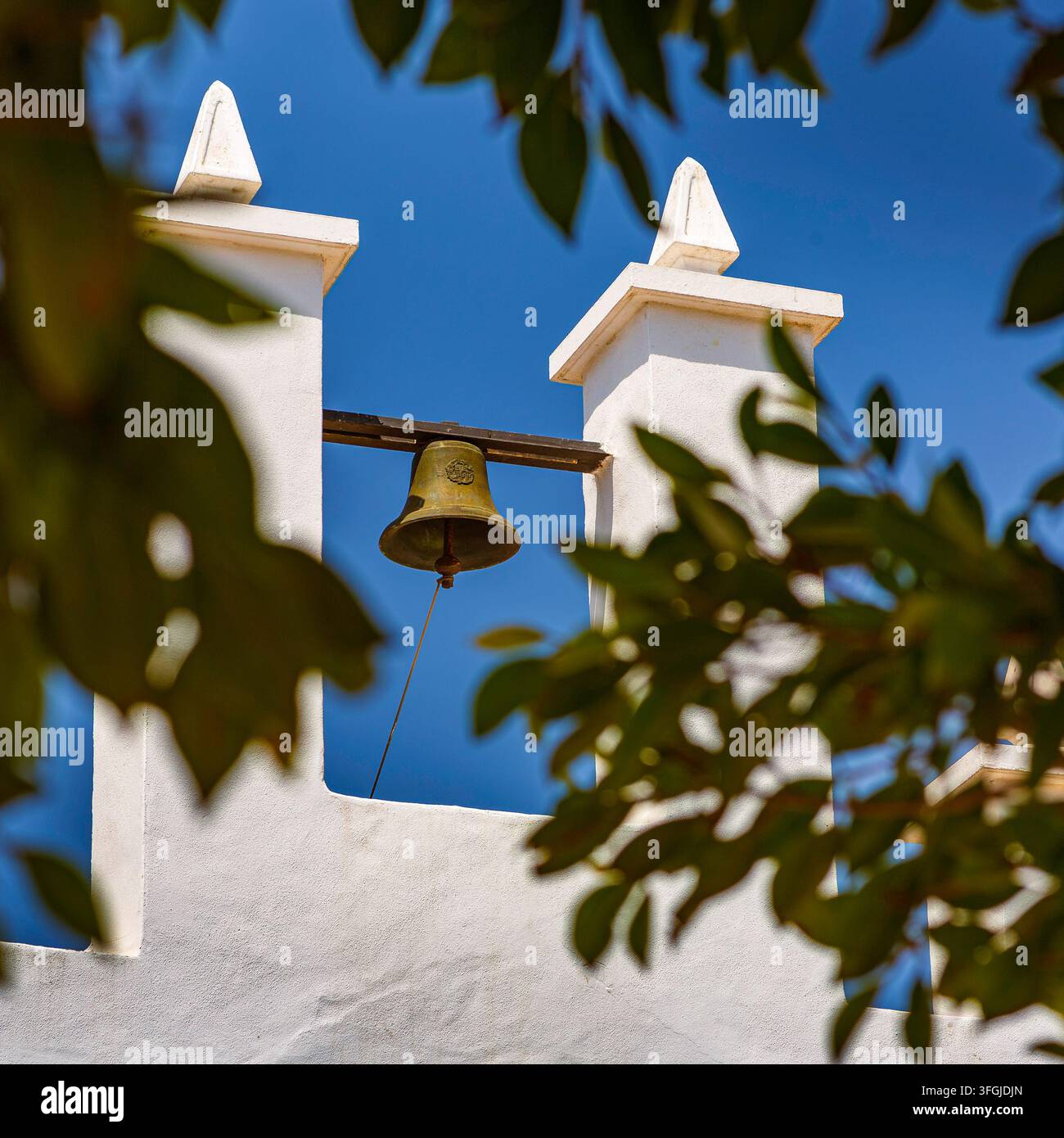 Murcie, Espagne – Une petite chapelle blanchie's à la chaux avec une architecture simple et un pignon à gradins se dresse sous un ciel bleu éclatant sur une côte méditerranéenne Banque D'Images