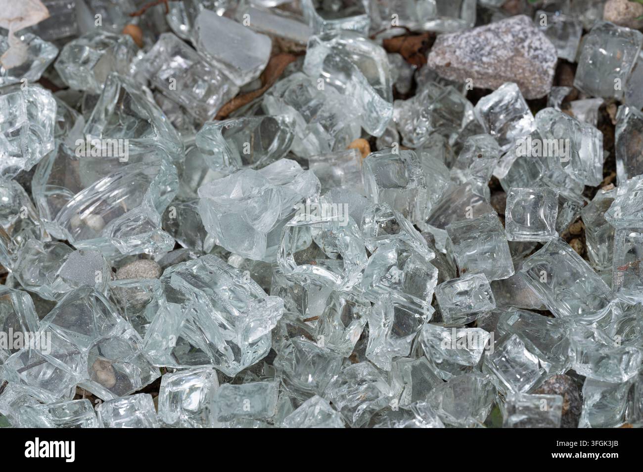 Gros plan de la texture de fragments de verre décoratif transparent mélangés à de petites pierres en extérieur. Les surfaces réfléchissantes créent un arrière-plan cristallin abstrait Banque D'Images