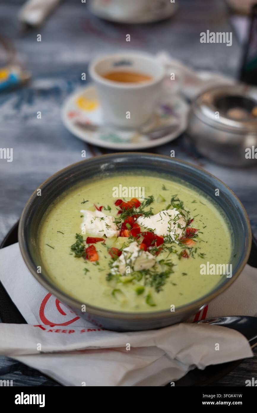 Soupe froide d'avocat et concombre dans un bol avec une tasse d'espresso fraîche. Soupe crémeuse verte vegan crue saine garnie de poivron rouge et d'aneth frais. Banque D'Images