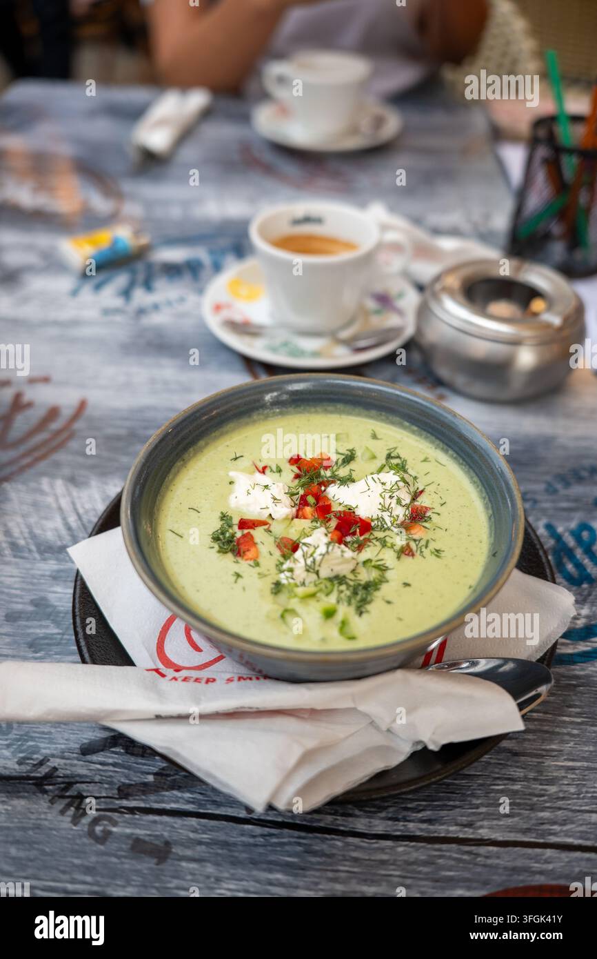 Soupe froide d'avocat et concombre dans un bol avec une tasse d'espresso fraîche. Soupe crémeuse verte vegan crue saine garnie de poivron rouge et d'aneth frais. Banque D'Images