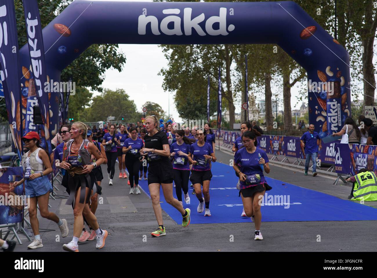 Coureuses en tenues festives assorties célébrant à l'arrivée de l'événement de course féminine La Parisienne sur une rue de Paris en France. Banque D'Images