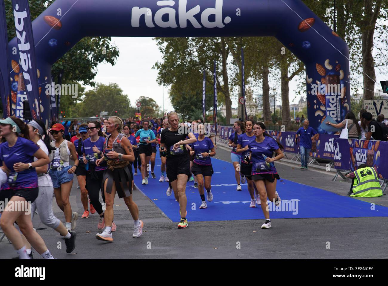 Coureuses en tenues festives assorties célébrant à l'arrivée de l'événement de course féminine La Parisienne sur une rue de Paris en France. Banque D'Images