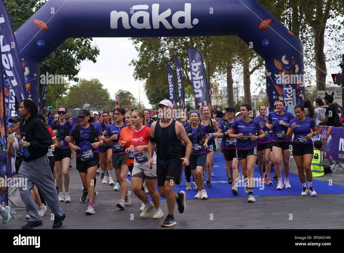 Coureuses en tenues festives assorties célébrant à l'arrivée de l'événement de course féminine La Parisienne sur une rue de Paris en France. Banque D'Images
