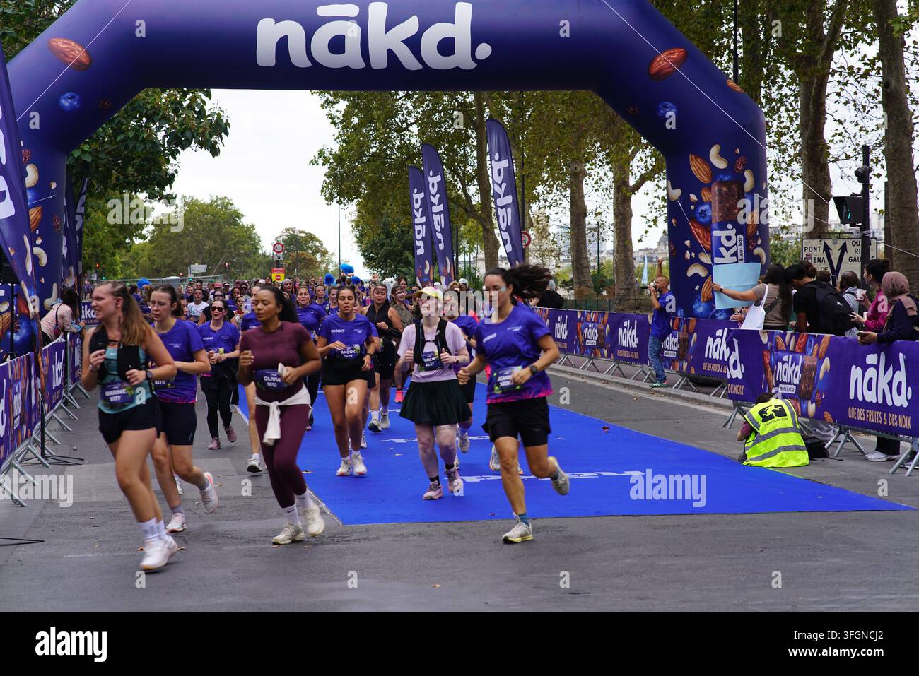 Coureuses en tenues festives assorties célébrant à l'arrivée de l'événement de course féminine La Parisienne sur une rue de Paris en France. Banque D'Images