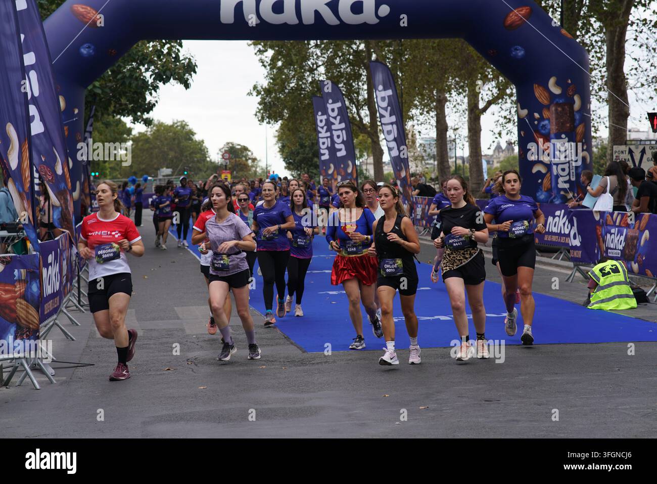 Coureuses en tenues festives assorties célébrant à l'arrivée de l'événement de course féminine La Parisienne sur une rue de Paris en France. Banque D'Images