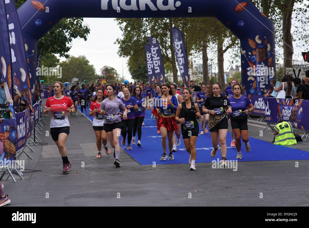 Coureuses en tenues festives assorties célébrant à l'arrivée de l'événement de course féminine La Parisienne sur une rue de Paris en France. Banque D'Images