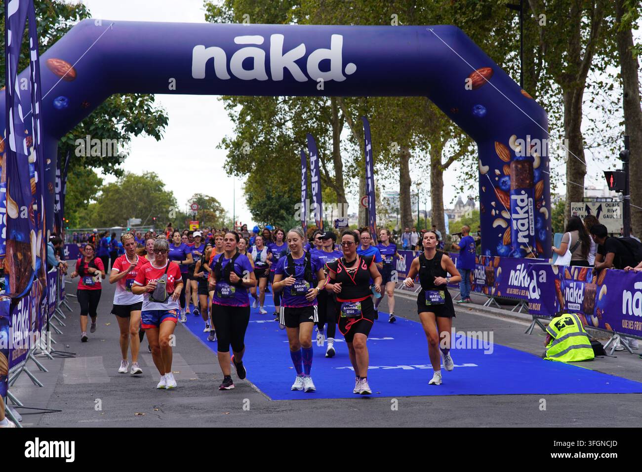 Coureuses en tenues festives assorties célébrant à l'arrivée de l'événement de course féminine La Parisienne sur une rue de Paris en France. Banque D'Images