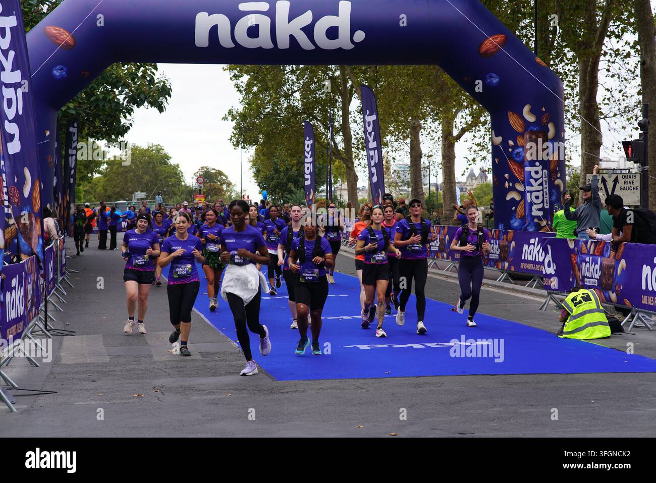 Coureuses en tenues festives assorties célébrant à l'arrivée de l'événement de course féminine La Parisienne sur une rue de Paris en France. Banque D'Images