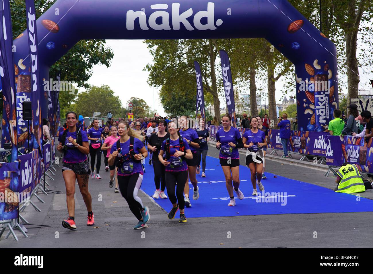Coureuses en tenues festives assorties célébrant à l'arrivée de l'événement de course féminine La Parisienne sur une rue de Paris en France. Banque D'Images