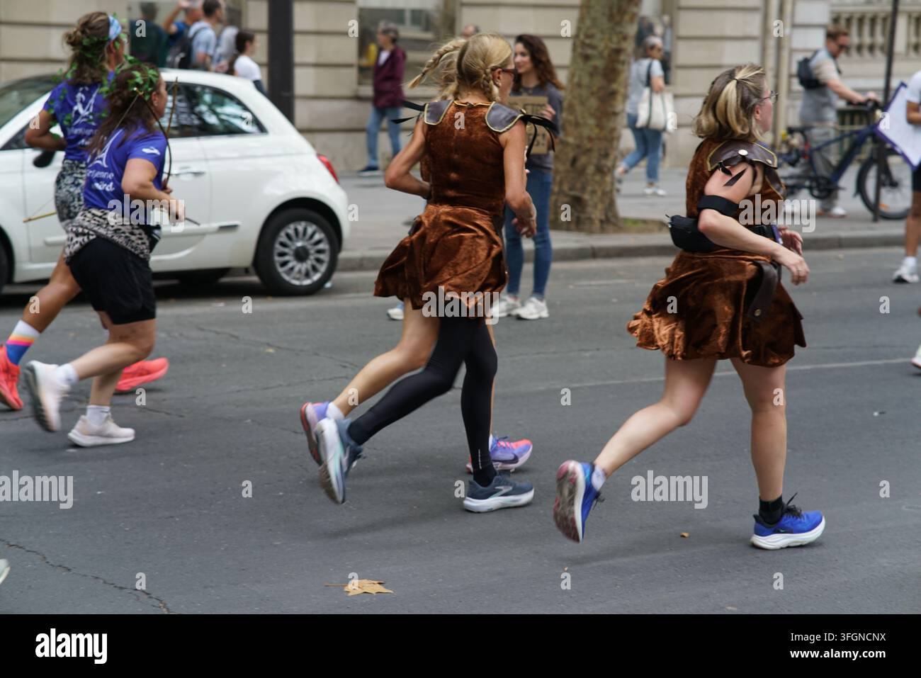 Coureuses en tenues festives assorties célébrant à l'arrivée de l'événement de course féminine La Parisienne sur une rue de Paris en France. Banque D'Images