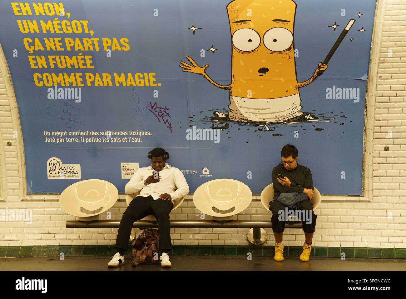 Deux hommes assis sur un banc du métro sous une affiche anti-cigarette sur un mur carrelé d'une station à Paris, France. Banque D'Images