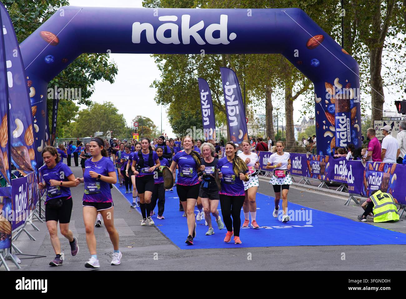 Coureuses en tenues festives assorties célébrant à l'arrivée de l'événement de course féminine La Parisienne sur une rue de Paris en France. Banque D'Images