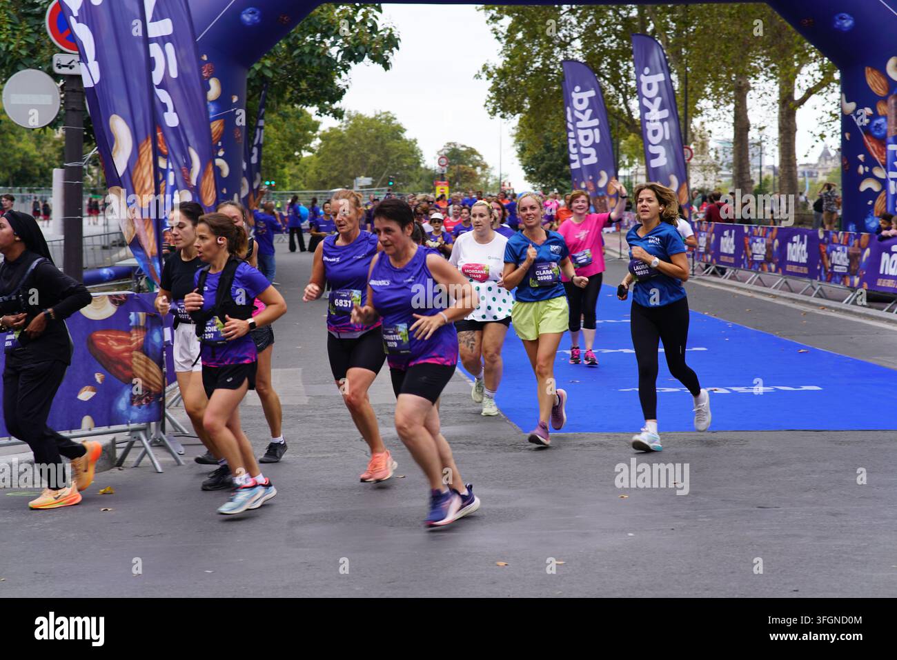 Coureuses en tenues festives assorties célébrant à l'arrivée de l'événement de course féminine La Parisienne sur une rue de Paris en France. Banque D'Images