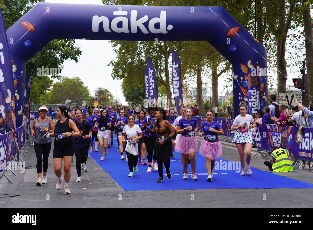Coureuses en tenues festives assorties célébrant à l'arrivée de l'événement de course féminine La Parisienne sur une rue de Paris en France. Banque D'Images