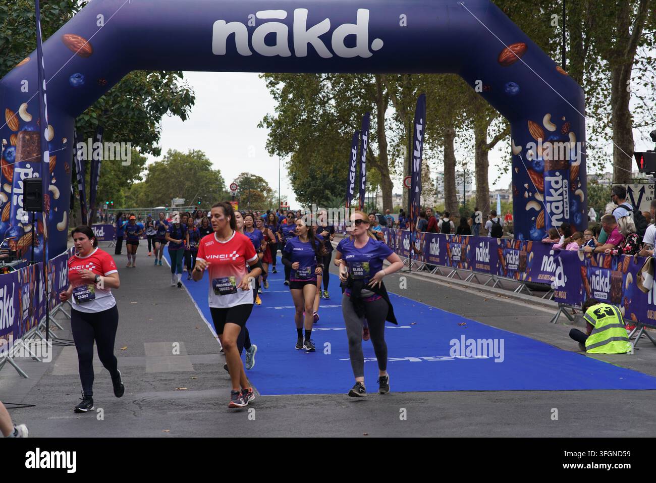 Coureuses en tenues festives assorties célébrant à l'arrivée de l'événement de course féminine La Parisienne sur une rue de Paris en France. Banque D'Images