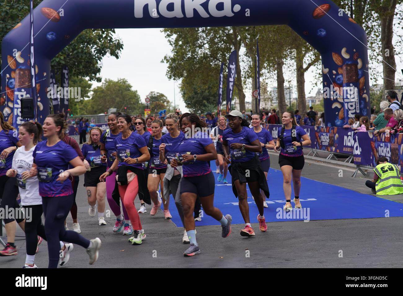 Coureuses en tenues festives assorties célébrant à l'arrivée de l'événement de course féminine La Parisienne sur une rue de Paris en France. Banque D'Images