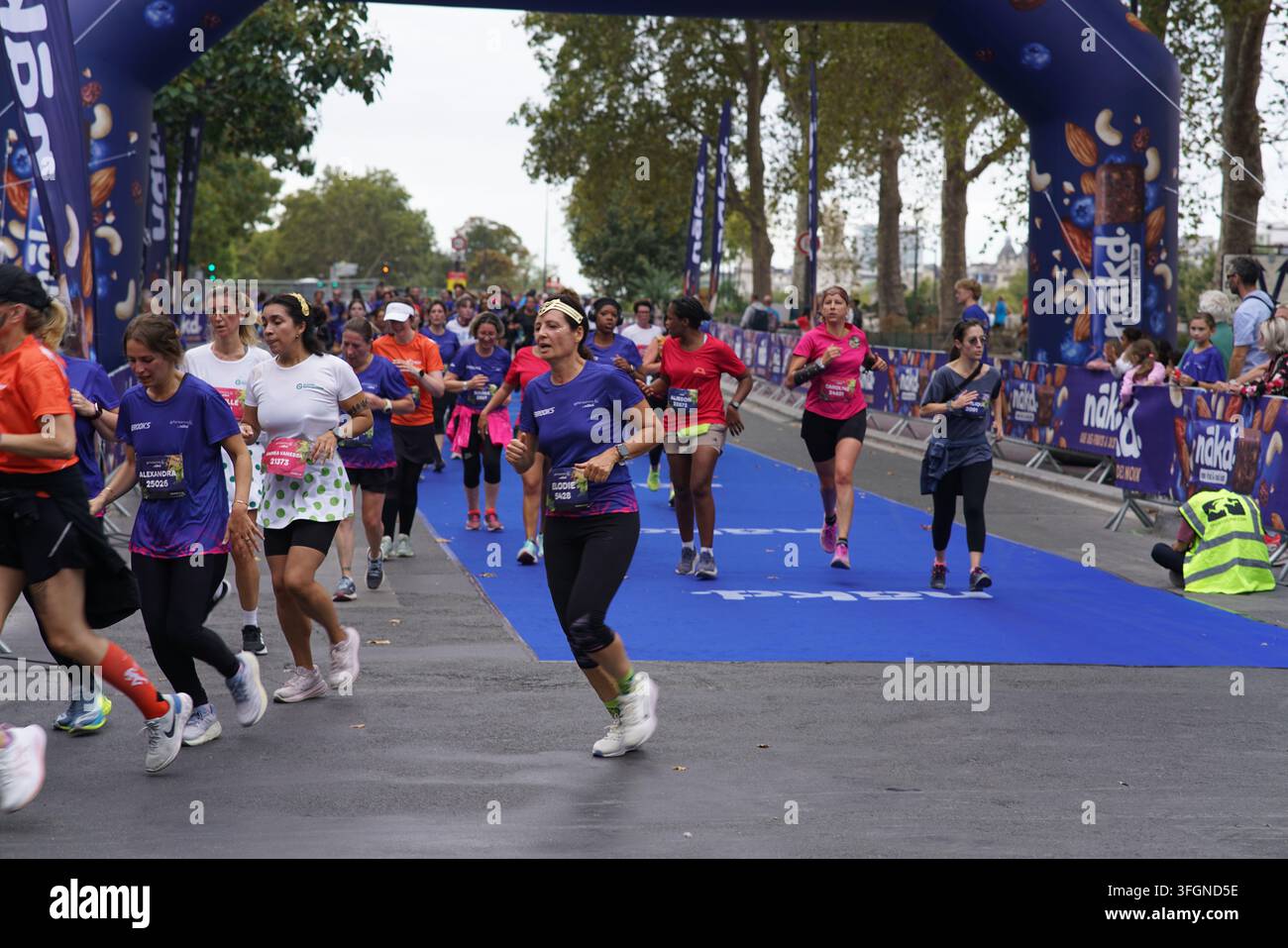Coureuses en tenues festives assorties célébrant à l'arrivée de l'événement de course féminine La Parisienne sur une rue de Paris en France. Banque D'Images