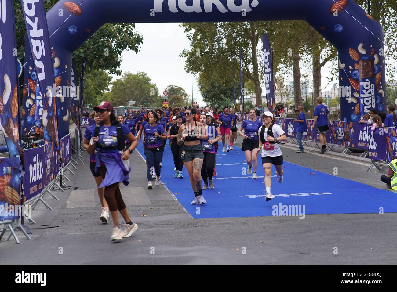 Coureuses en tenues festives assorties célébrant à l'arrivée de l'événement de course féminine La Parisienne sur une rue de Paris en France. Banque D'Images