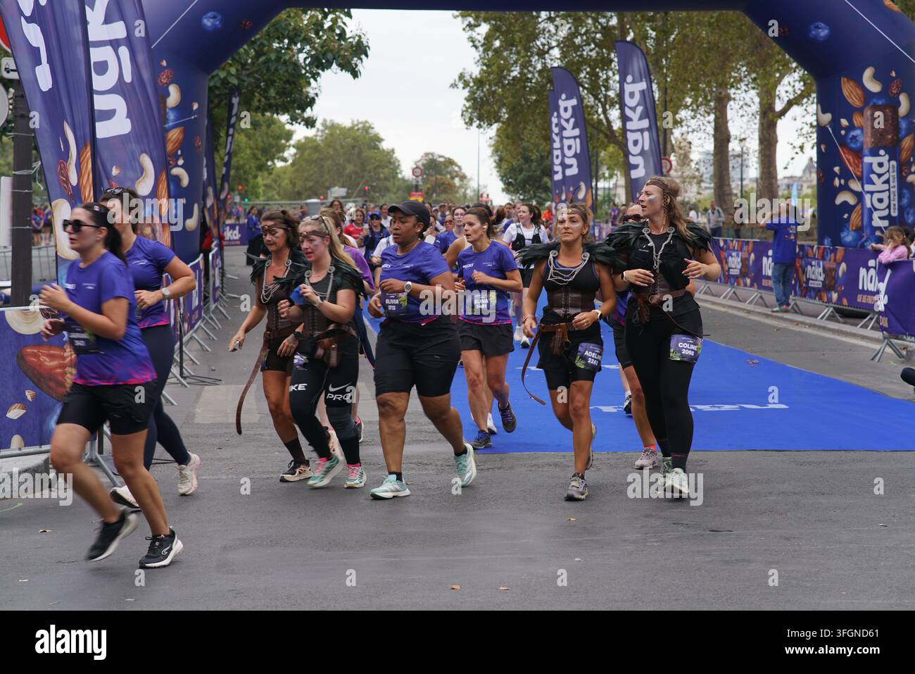 Coureuses en tenues festives assorties célébrant à l'arrivée de l'événement de course féminine La Parisienne sur une rue de Paris en France. Banque D'Images