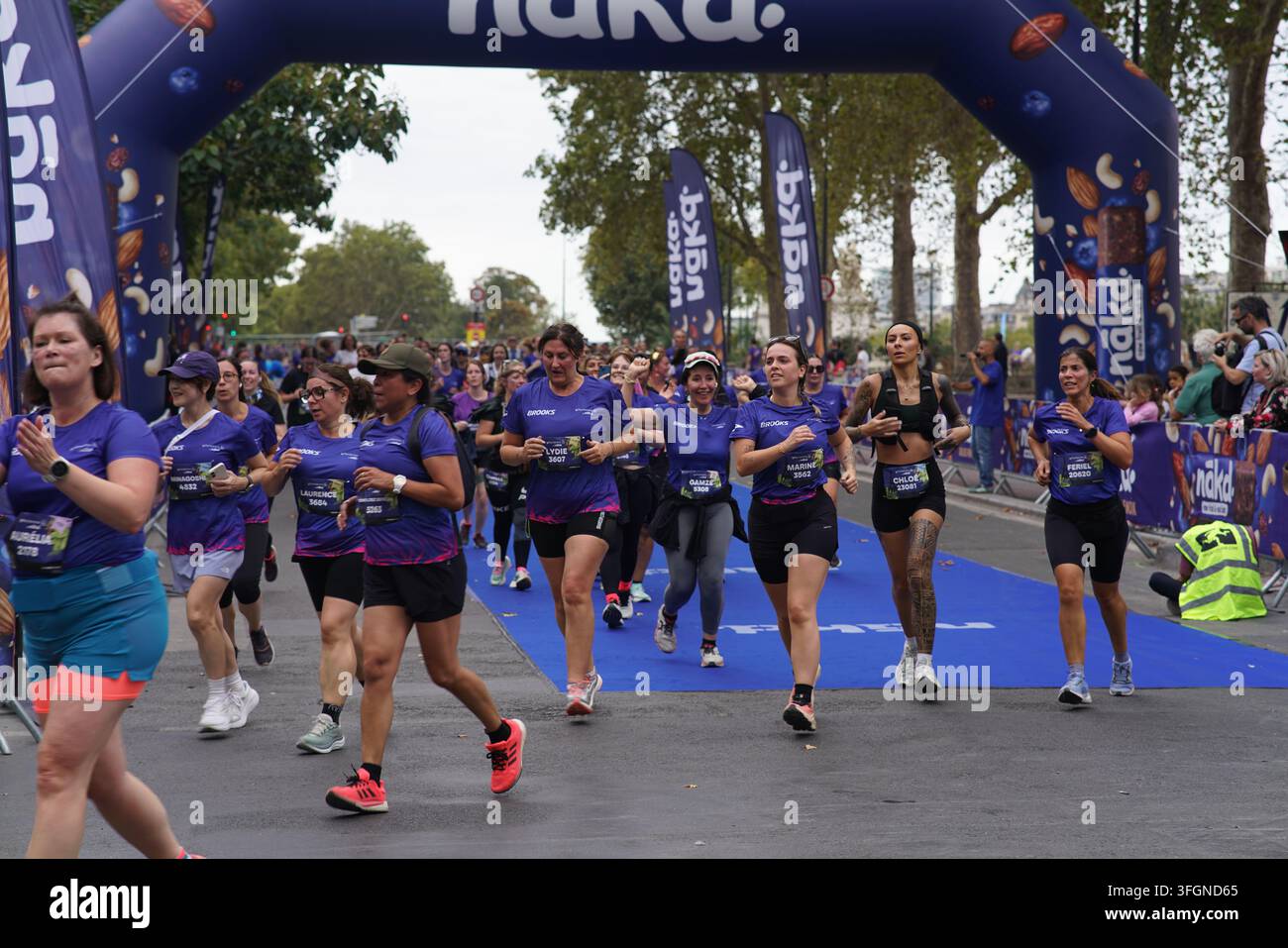 Coureuses en tenues festives assorties célébrant à l'arrivée de l'événement de course féminine La Parisienne sur une rue de Paris en France. Banque D'Images