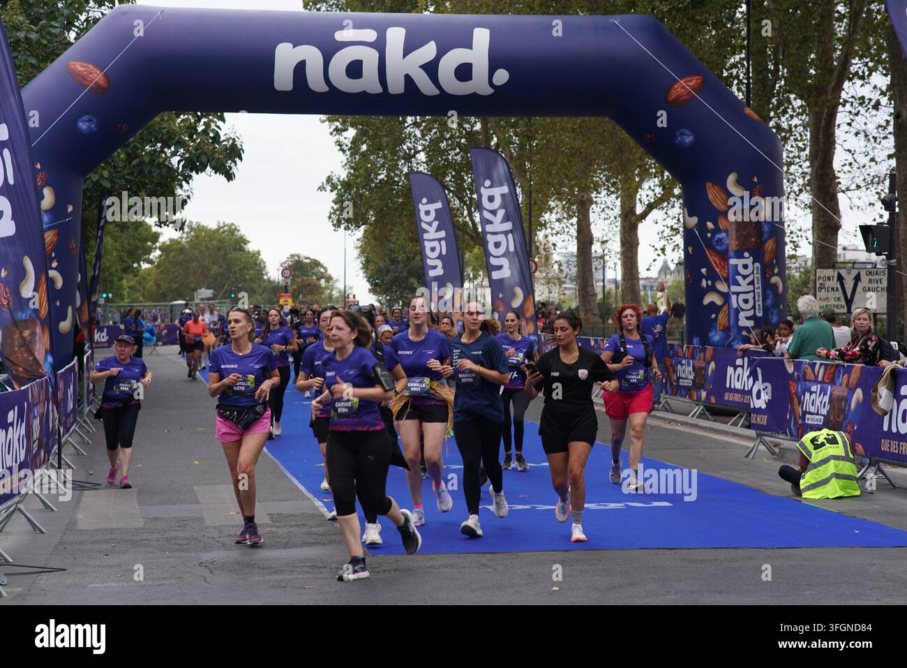 Coureuses en tenues festives assorties célébrant à l'arrivée de l'événement de course féminine La Parisienne sur une rue de Paris en France. Banque D'Images