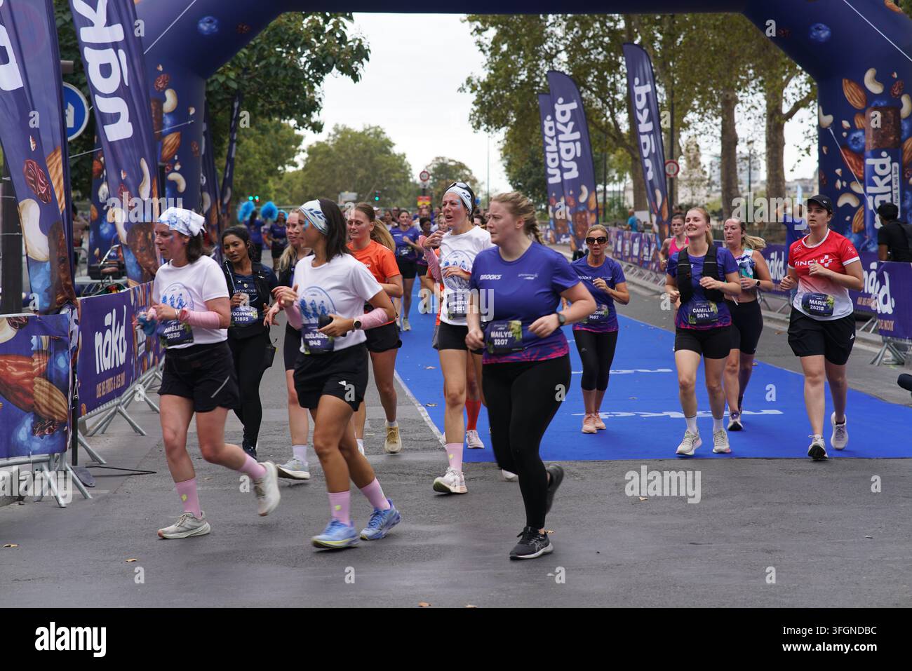 Coureuses en tenues festives assorties célébrant à l'arrivée de l'événement de course féminine La Parisienne sur une rue de Paris en France. Banque D'Images