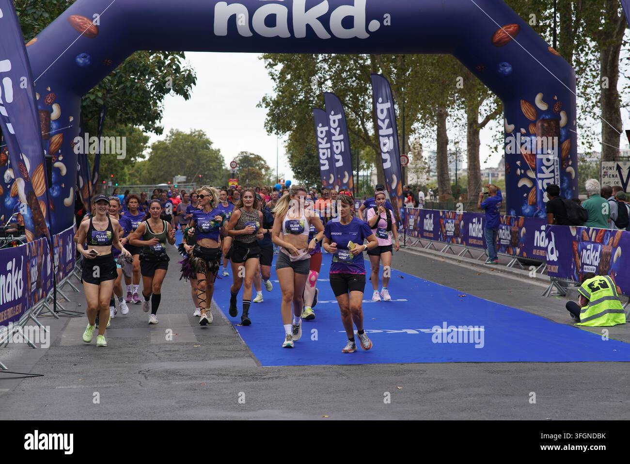 Coureuses en tenues festives assorties célébrant à l'arrivée de l'événement de course féminine La Parisienne sur une rue de Paris en France. Banque D'Images